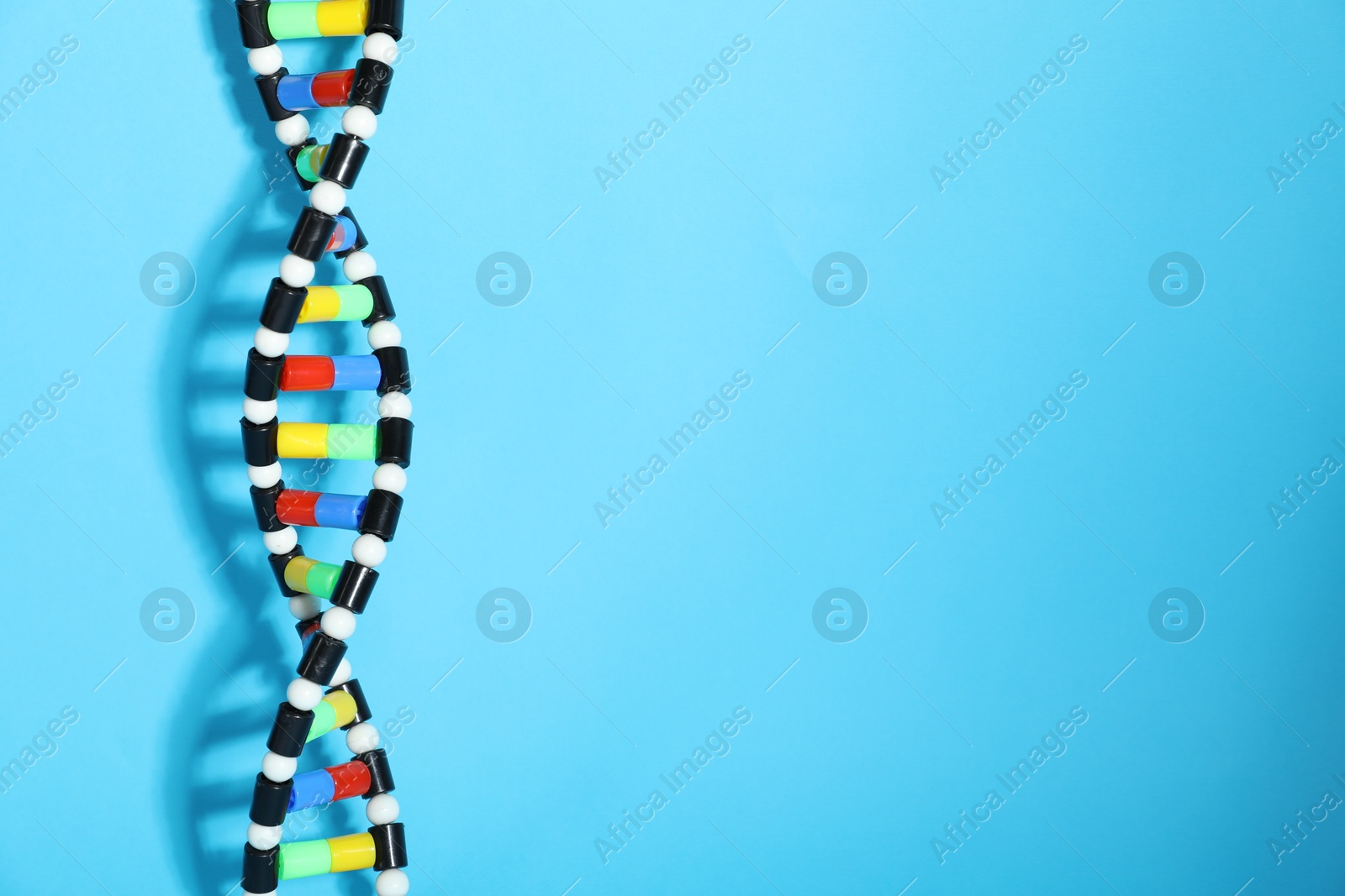 Photo of DNA structure model on light blue background, space for text