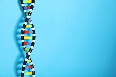 Photo of DNA structure model on light blue background, space for text