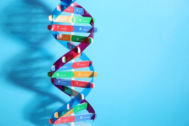 Photo of DNA structure model on light blue background, space for text