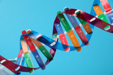 Photo of DNA structure model on light blue background, closeup