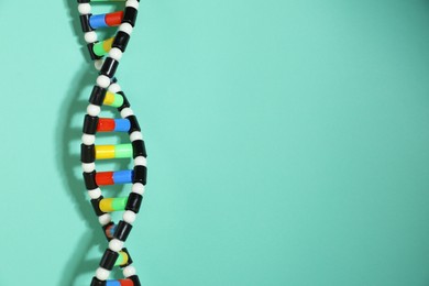 Photo of DNA structure model on turquoise background, space for text