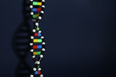 Photo of DNA structure model on dark background, space for text