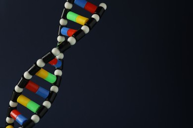 Photo of DNA structure model on dark background, closeup. Space for text