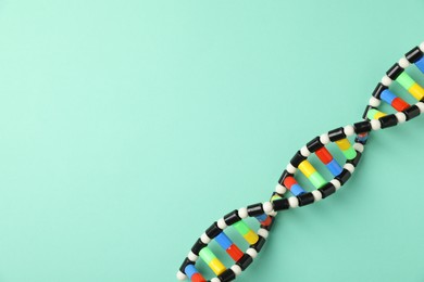 Photo of Colorful DNA structure model on turquoise background, top view. Space for text