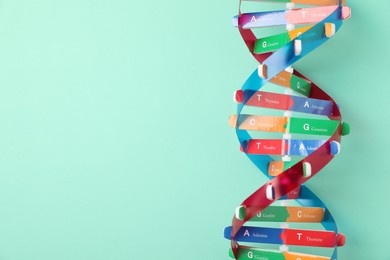 Photo of Colorful DNA structure model on turquoise background, top view. Space for text