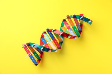 Photo of DNA structure model on yellow background, top view