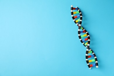 Photo of Colorful DNA structure model on light blue background, top view. Space for text