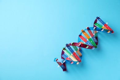 Photo of Colorful DNA structure model on light blue background, top view. Space for text