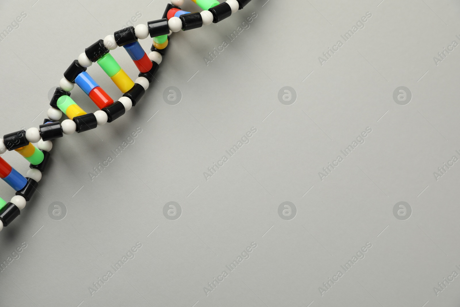 Photo of Colorful DNA structure model on light grey background, top view. Space for text