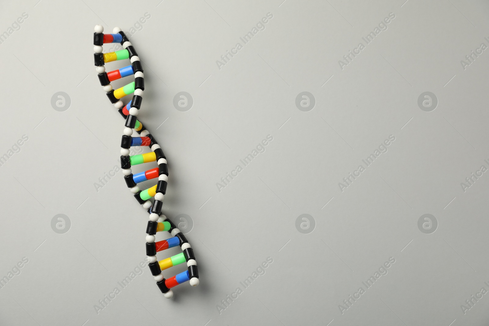 Photo of Colorful DNA structure model on light grey background, top view. Space for text