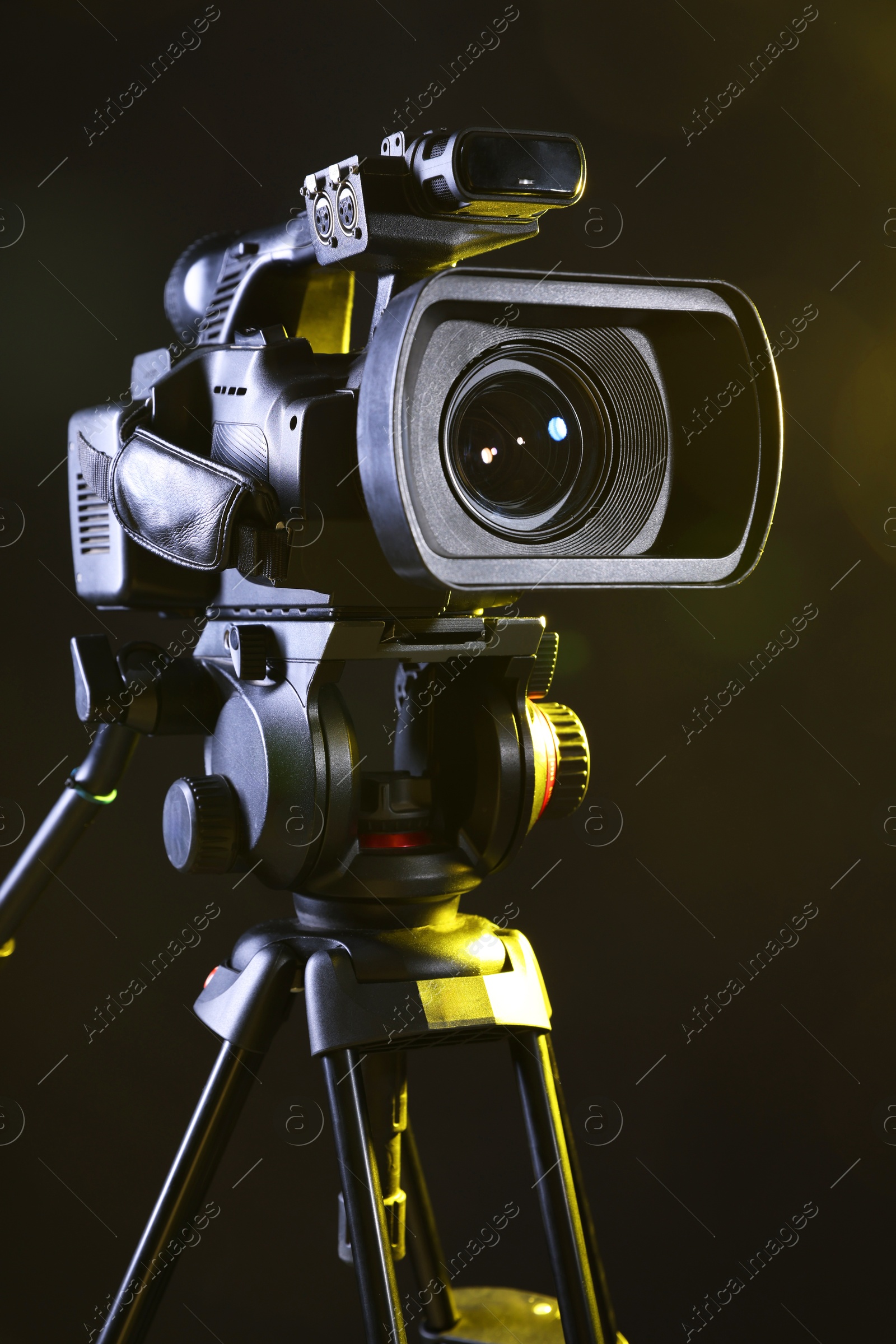 Photo of Modern video camera with tripod on black background, closeup