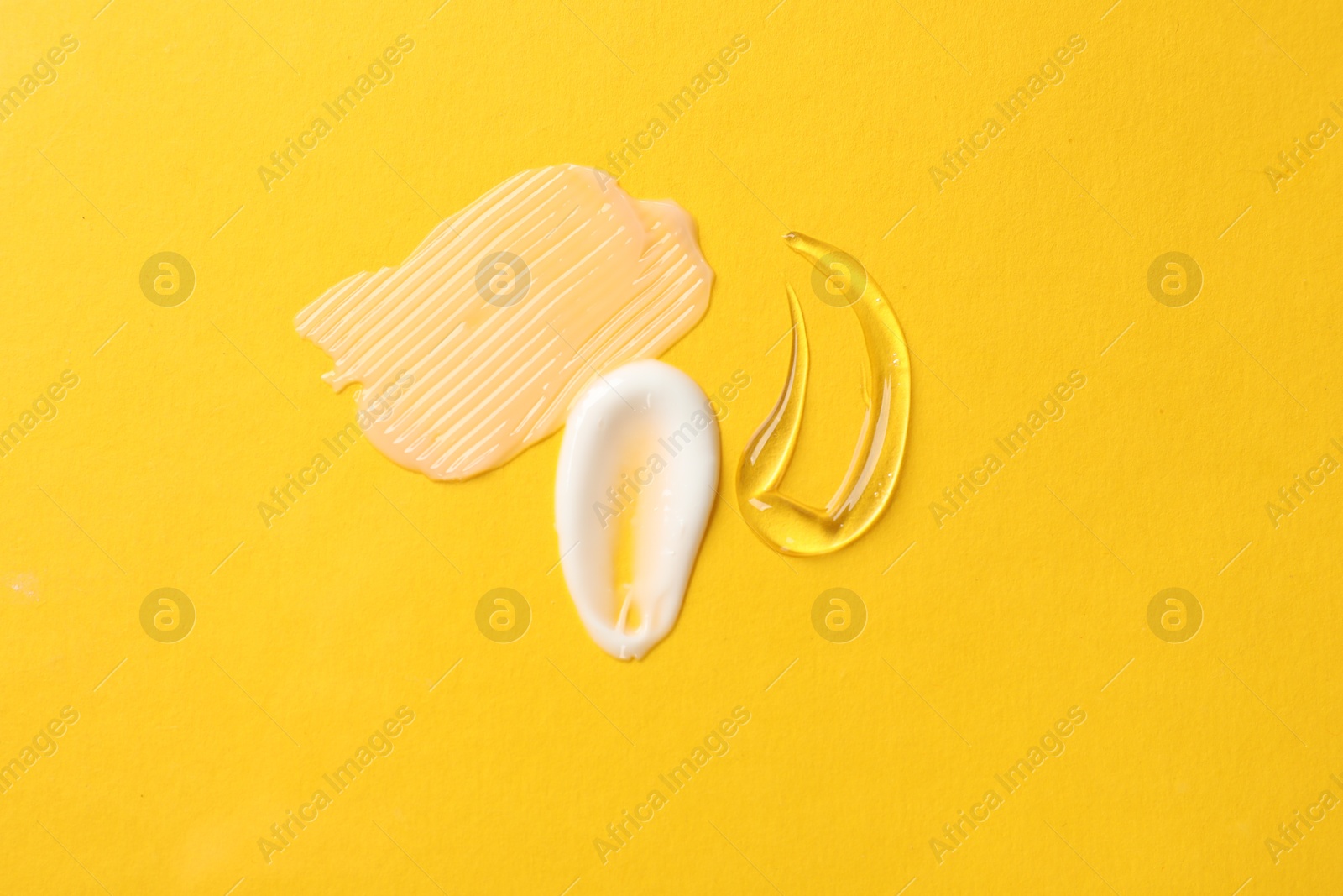 Photo of Samples of different cosmetic products on yellow background, flat lay