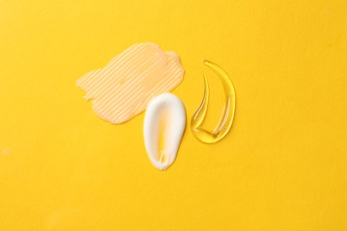 Photo of Samples of different cosmetic products on yellow background, flat lay