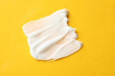 Photo of Sample of body cream on yellow background, top view