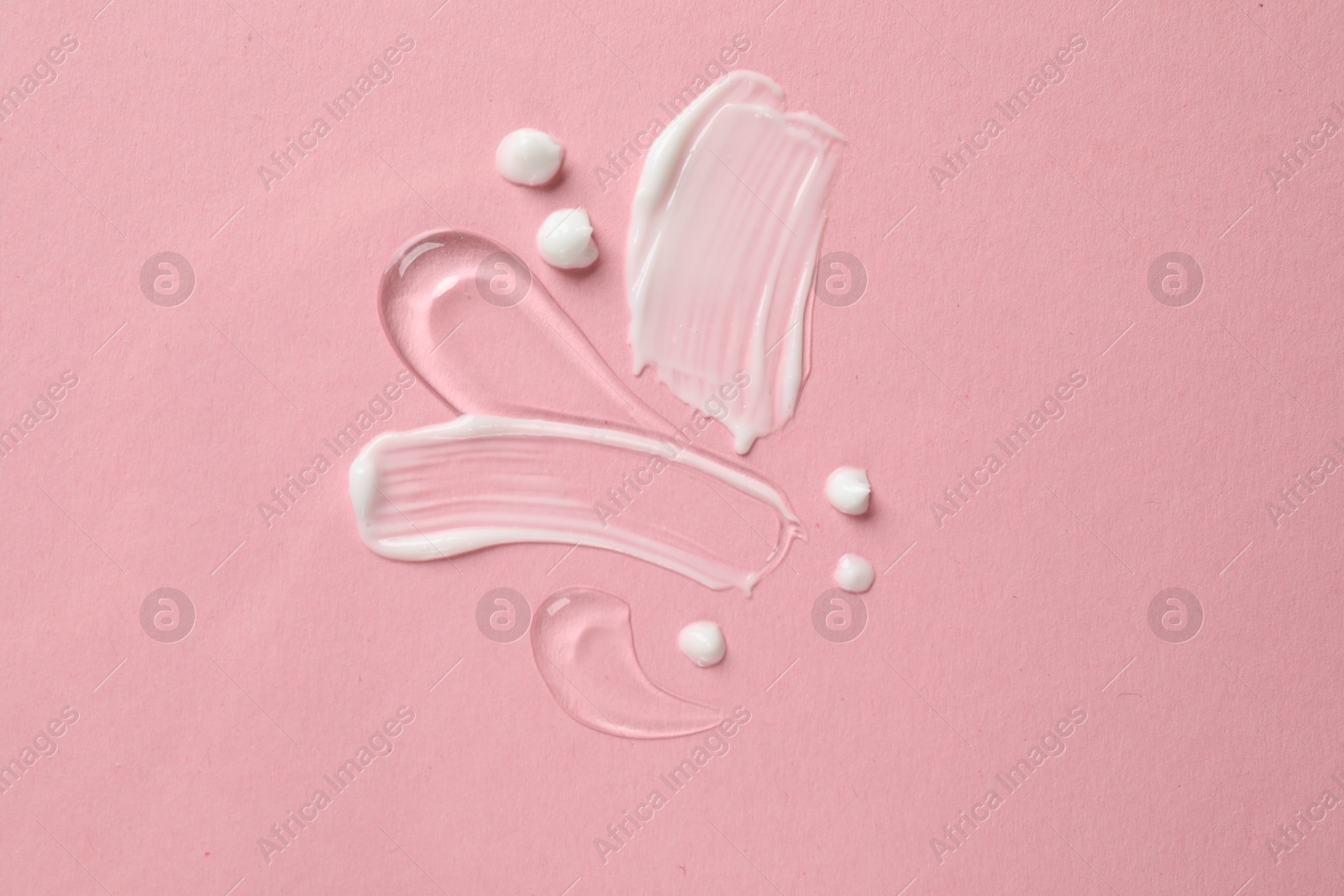 Photo of Samples of different cosmetic products on pink background, flat lay