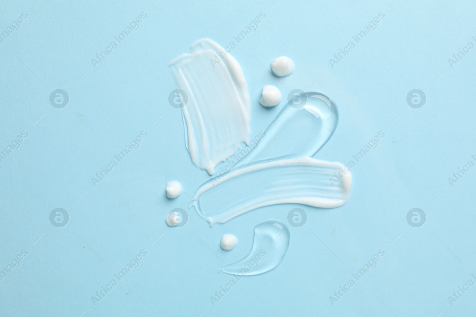 Photo of Samples of different cosmetic products on light blue background, flat lay