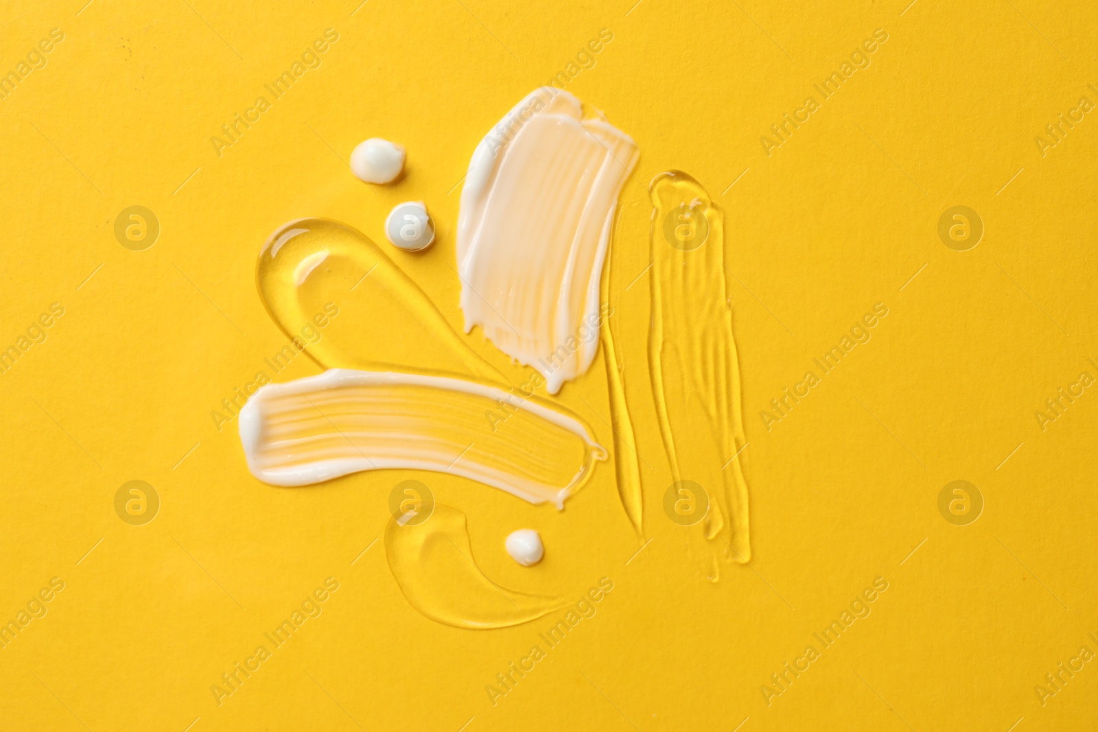 Photo of Samples of different cosmetic products on yellow background, flat lay