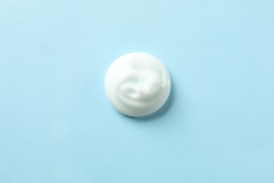 Photo of Sample of body cream on light blue background, top view