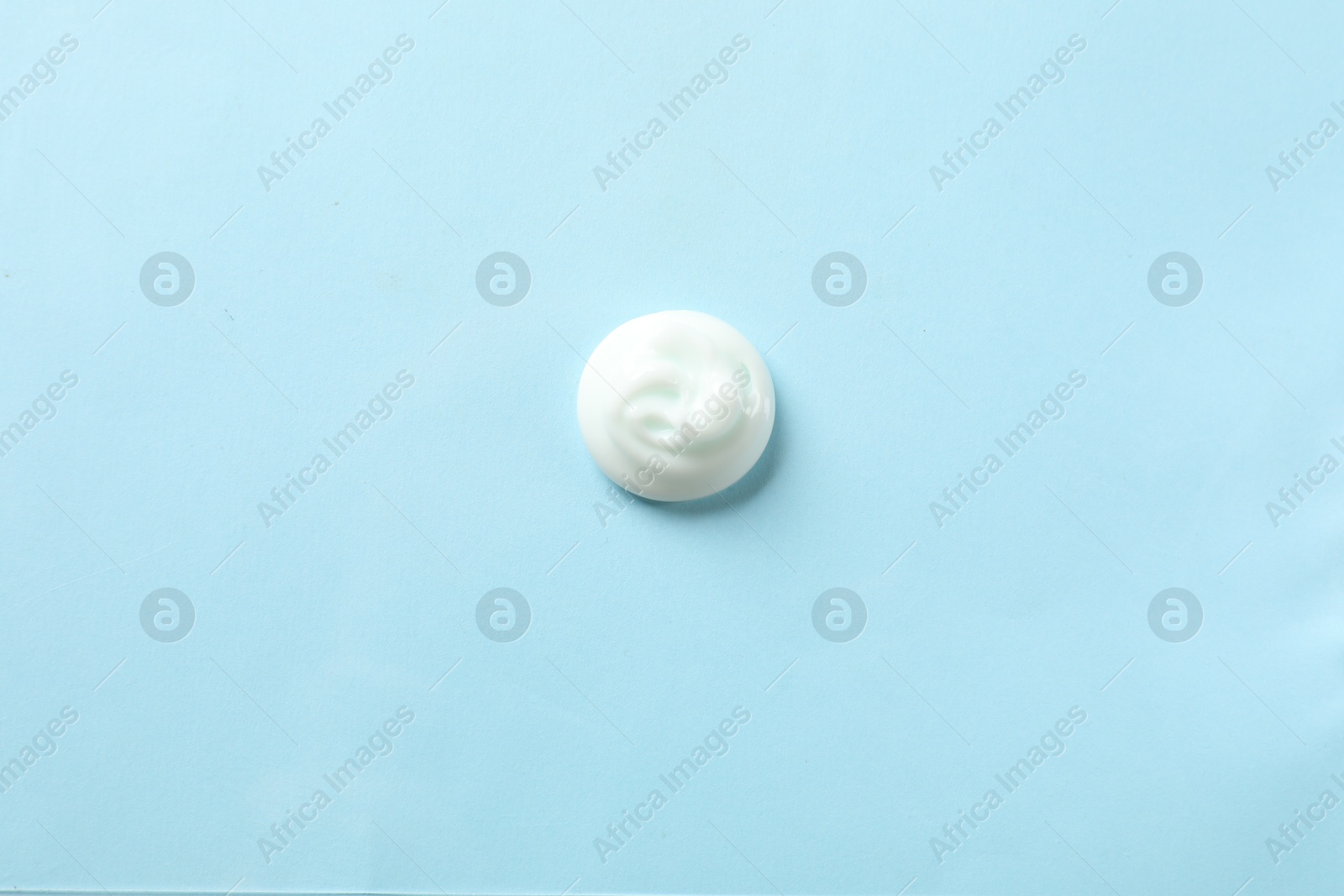 Photo of Sample of body cream on light blue background, top view