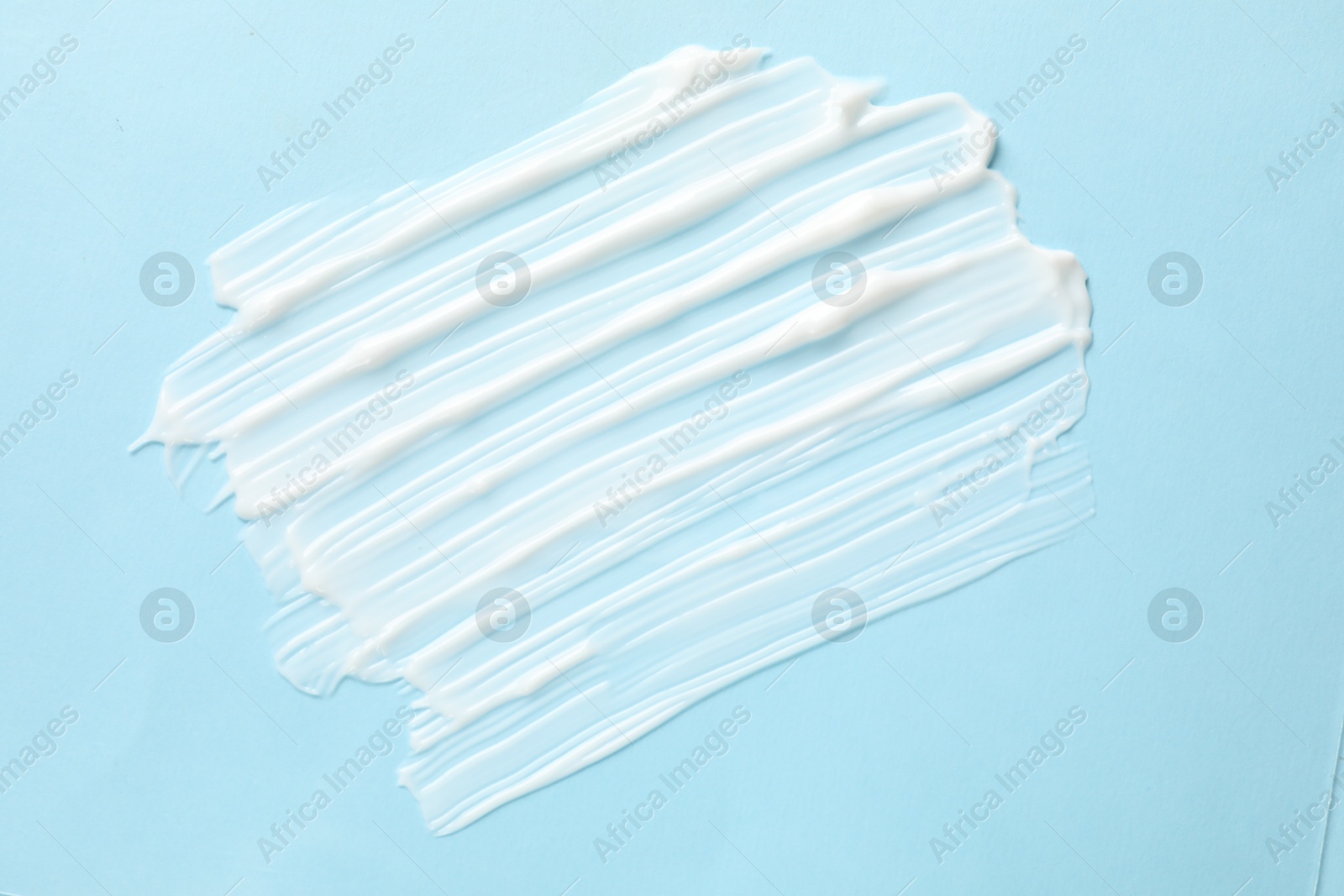 Photo of Sample of body cream on light blue background, top view