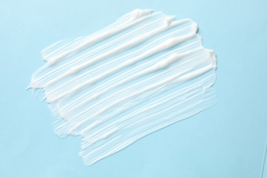 Photo of Sample of body cream on light blue background, top view