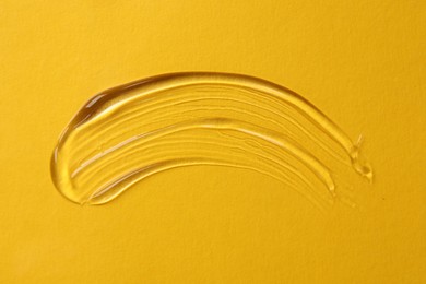 Photo of Sample of cosmetic product on yellow background, top view