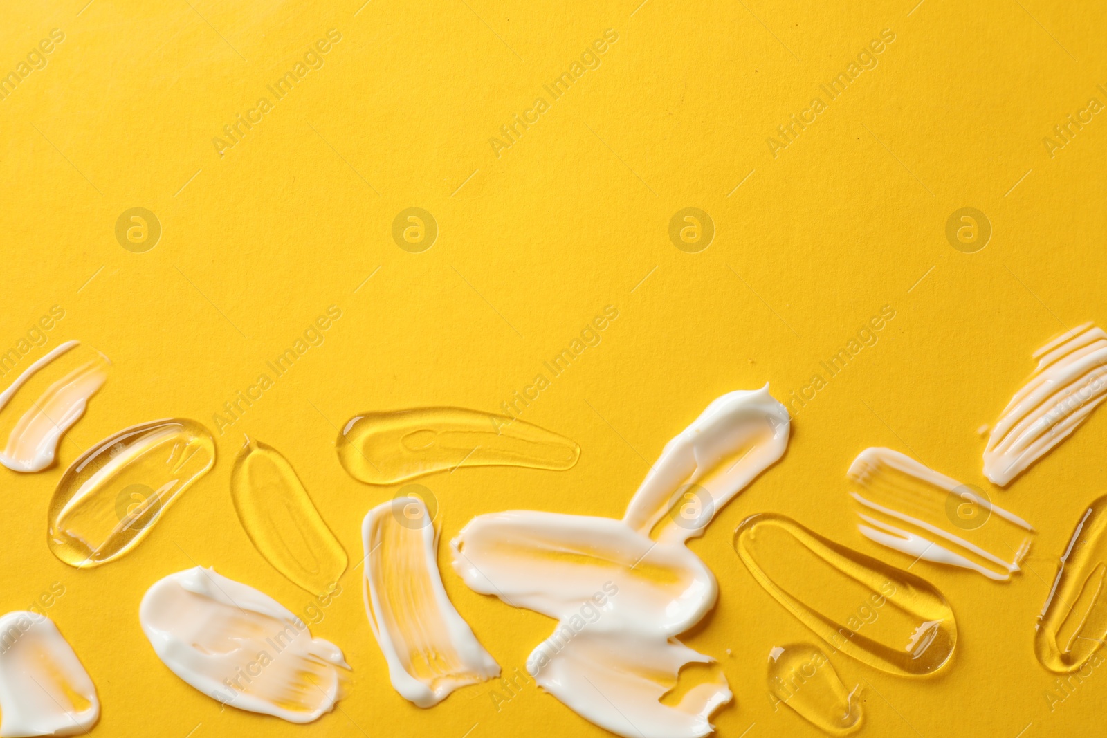 Photo of Samples of different cosmetic products on yellow background, flat lay. Space for text