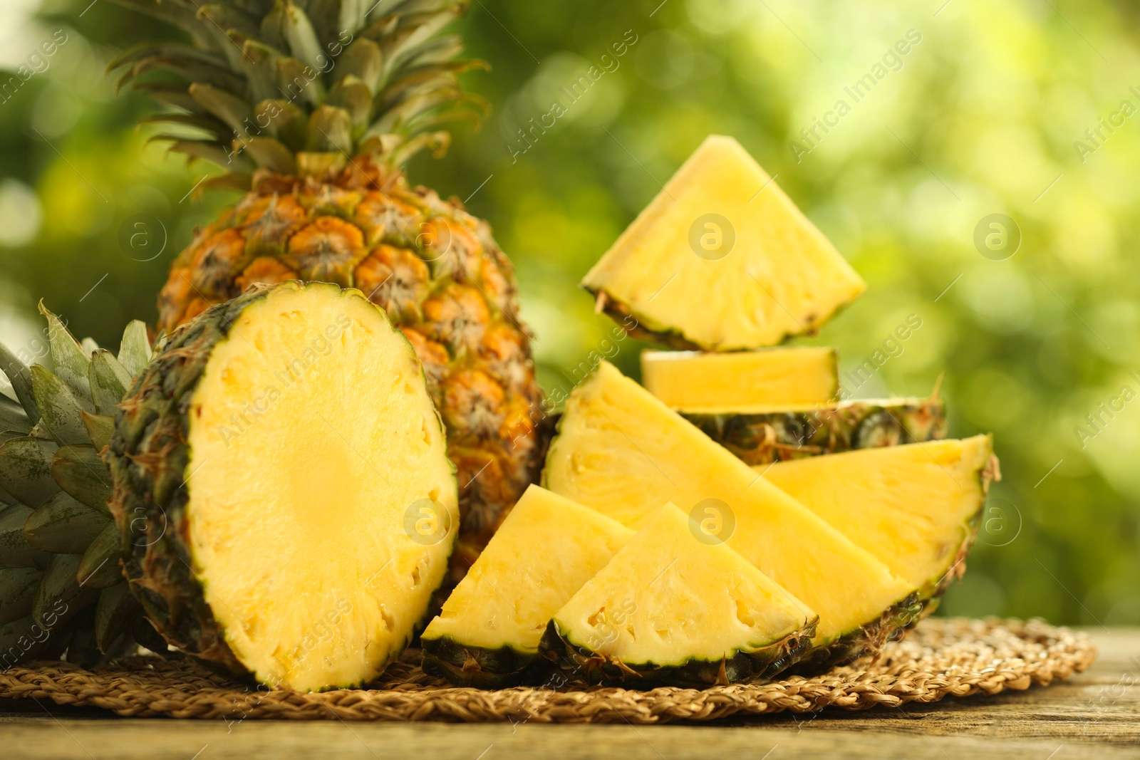 Photo of Fresh ripe pineapples on wooden table against blurred background, closeup