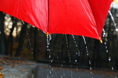 Photo of Open red umbrella under pouring rain outdoors, closeup