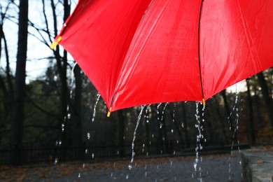 Photo of Open red umbrella under pouring rain outdoors, closeup