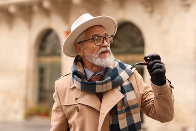 Photo of Stylish senior man with tobacco pipe on city street