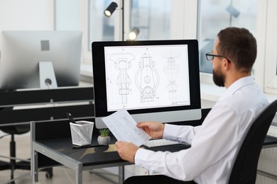 Photo of Technician making digital engineering drawing on computer at desk in office