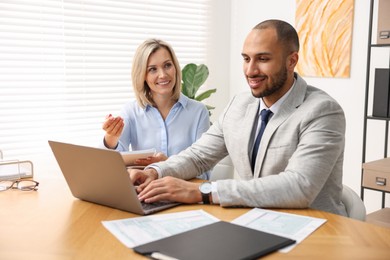 Photo of Coworkers with laptop working together in office