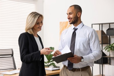 Photo of Coworkers with clipboard working together in office