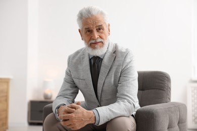 Photo of Portrait of handsome bearded man in armchair indoors