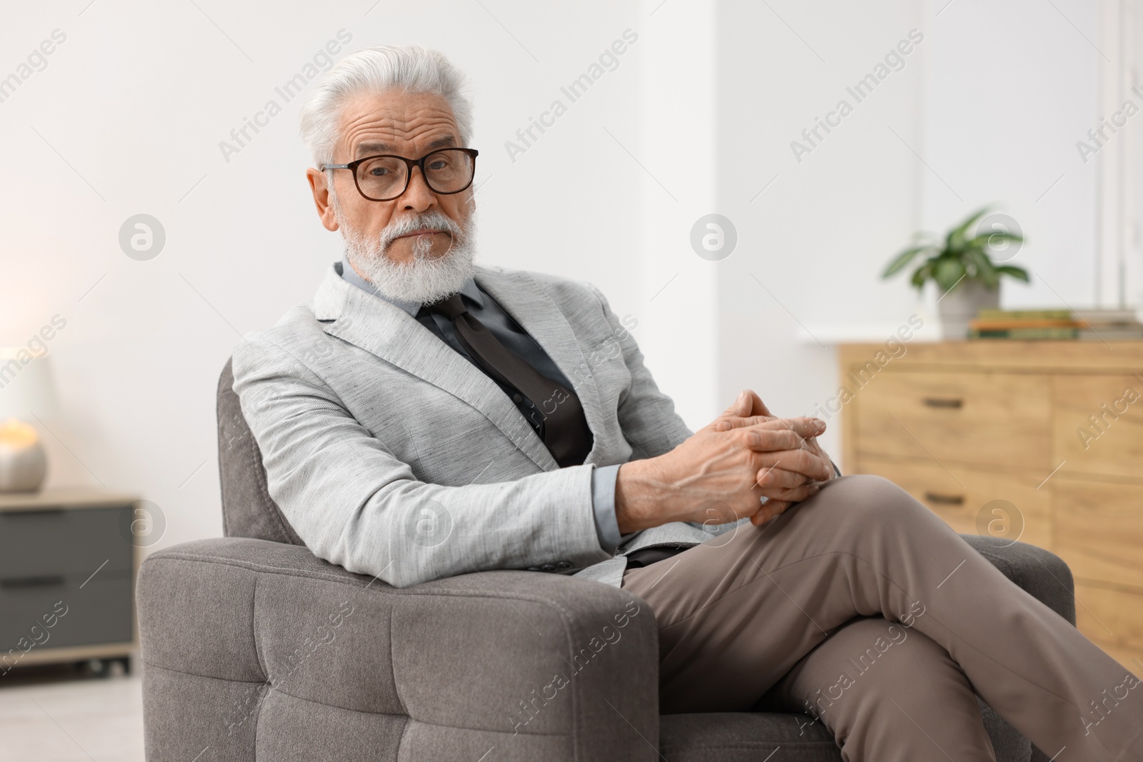 Photo of Portrait of handsome bearded man in armchair indoors