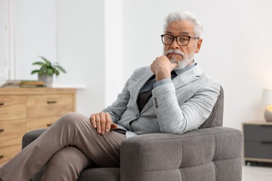 Photo of Portrait of handsome bearded man in armchair indoors