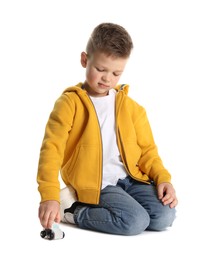 Little boy playing with toy car on white background