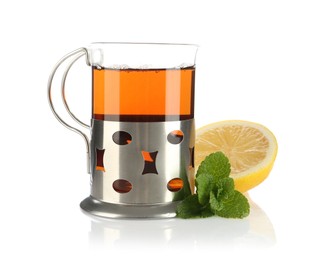 Photo of Glass of aromatic tea in holder, lemon and mint isolated on white