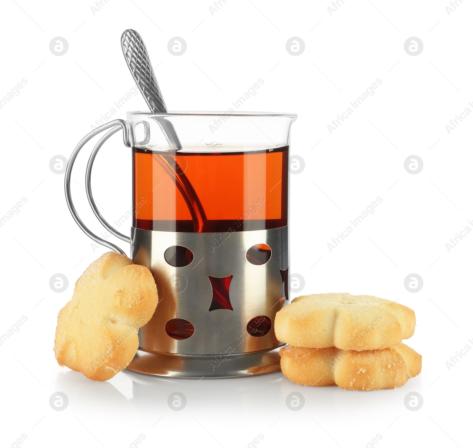 Photo of Glass of aromatic tea in holder, spoon and cookies isolated on white