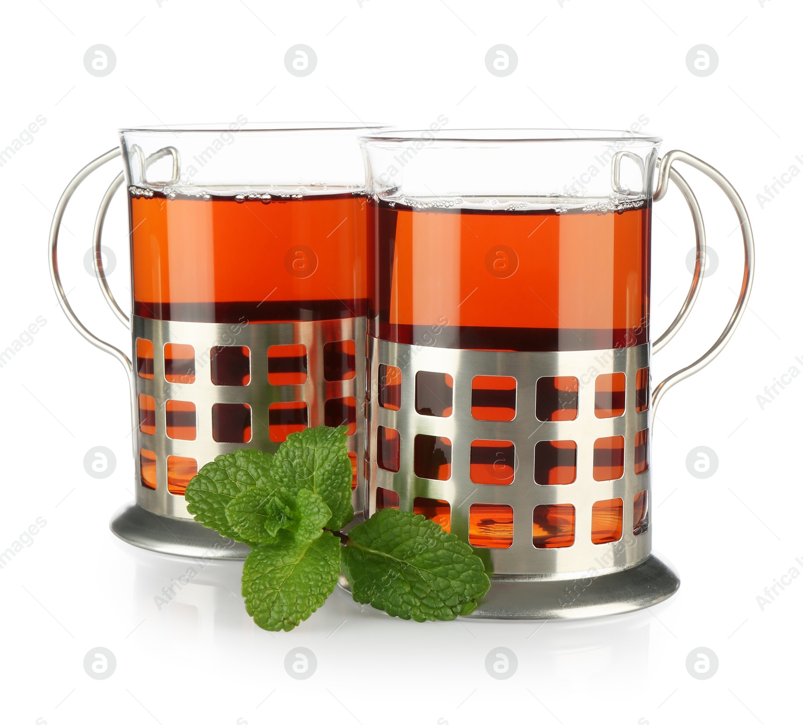 Photo of Glasses of aromatic tea in holders and mint isolated on white