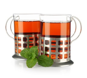 Photo of Glasses of aromatic tea in holders and mint isolated on white