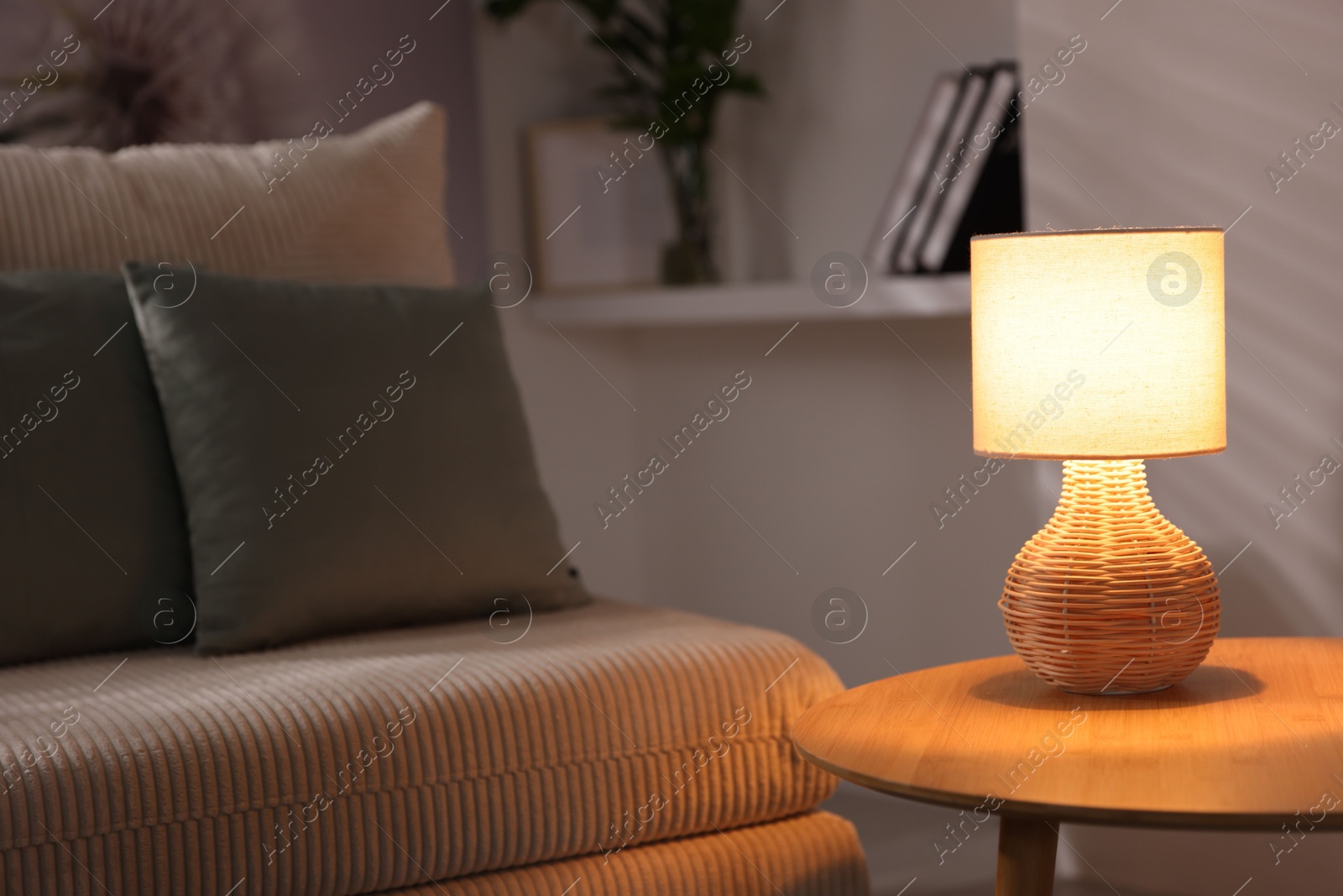 Photo of Stylish night lamp on wooden table and sofa in room. Interior design