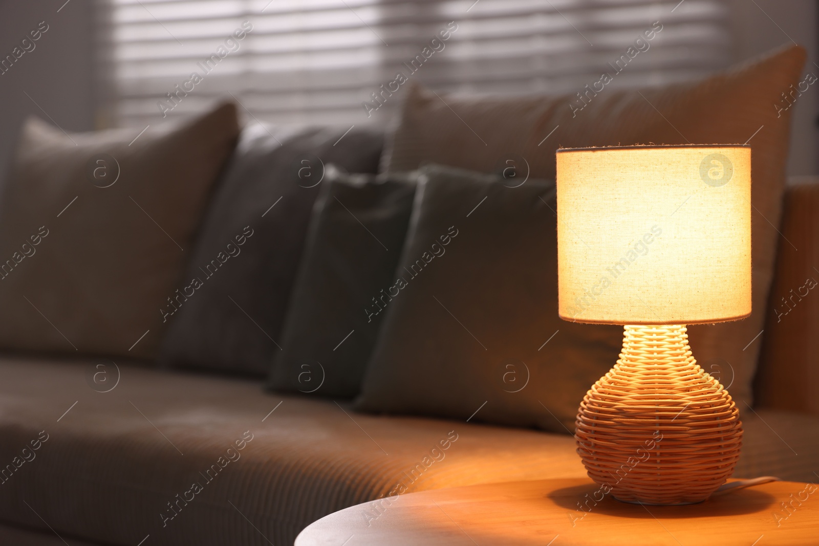 Photo of Stylish night lamp on wooden table and sofa in room, space for text