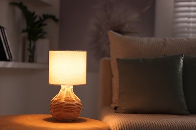 Photo of Stylish night lamp on wooden table and sofa in room. Interior design