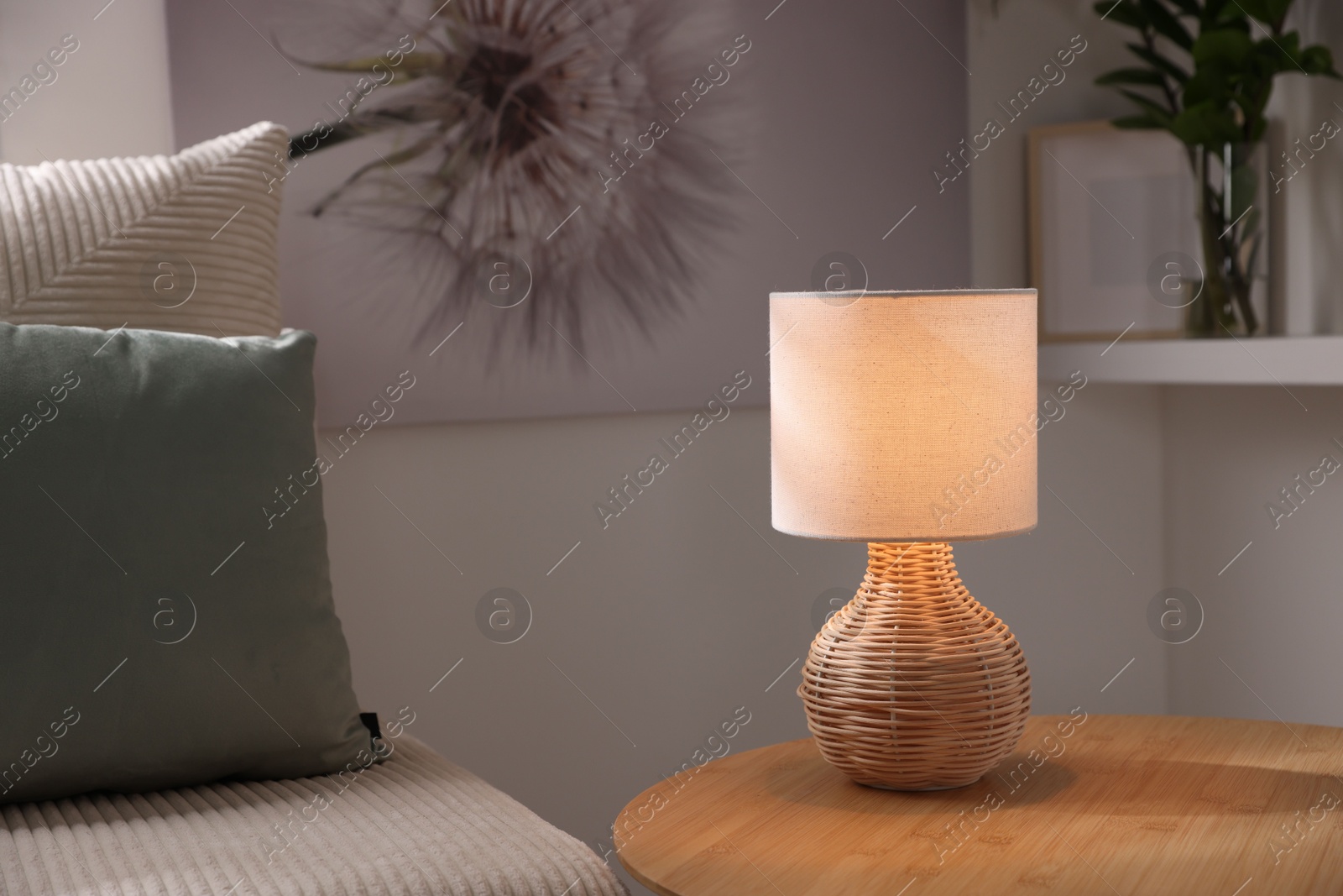 Photo of Stylish night lamp on wooden table and sofa in room. Interior design