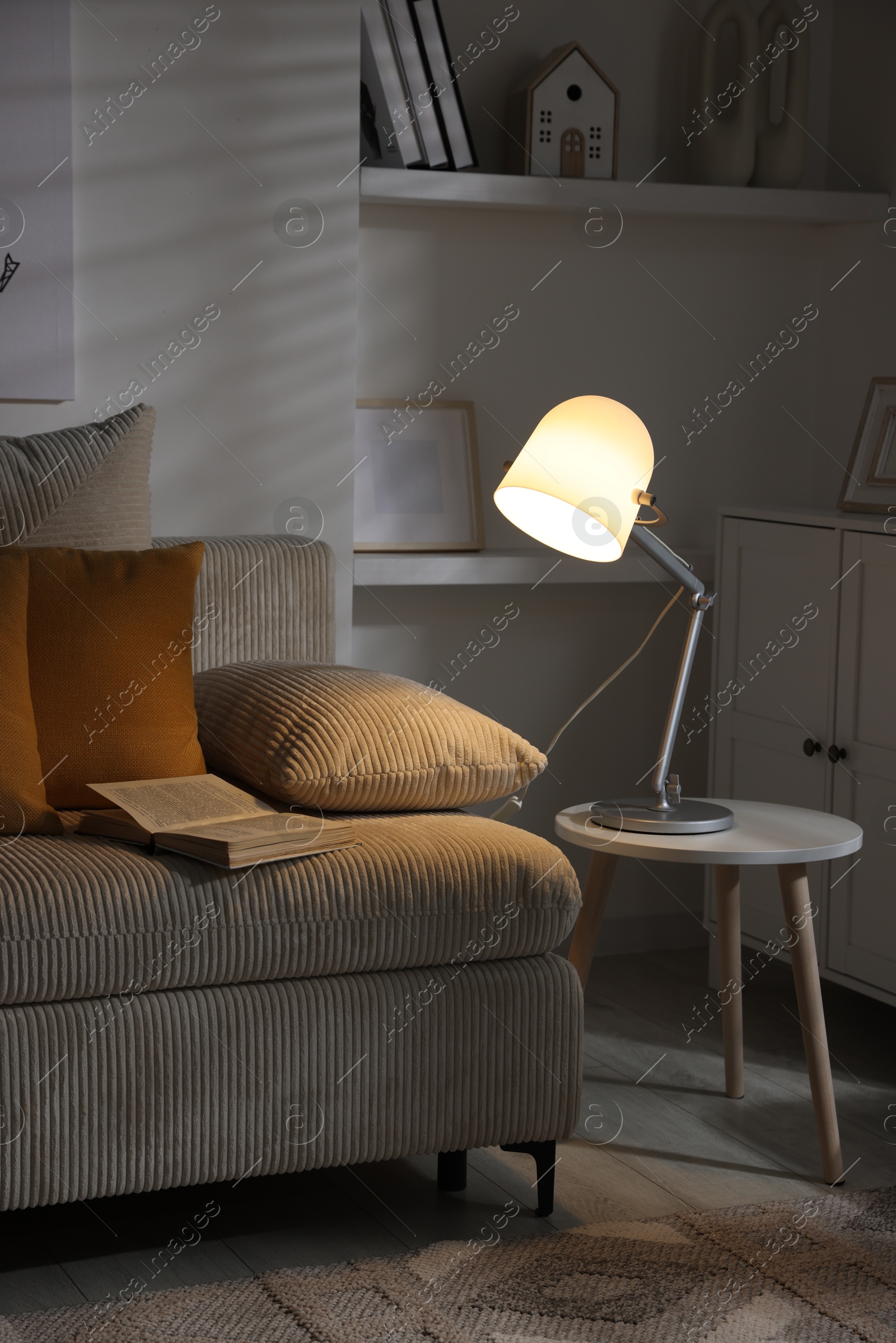 Photo of Stylish night lamp on side table near sofa in room. Interior design