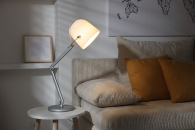 Photo of Stylish night lamp on side table near sofa in room. Interior design