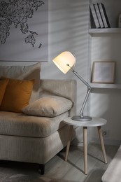 Photo of Stylish night lamp on side table near sofa in room. Interior design