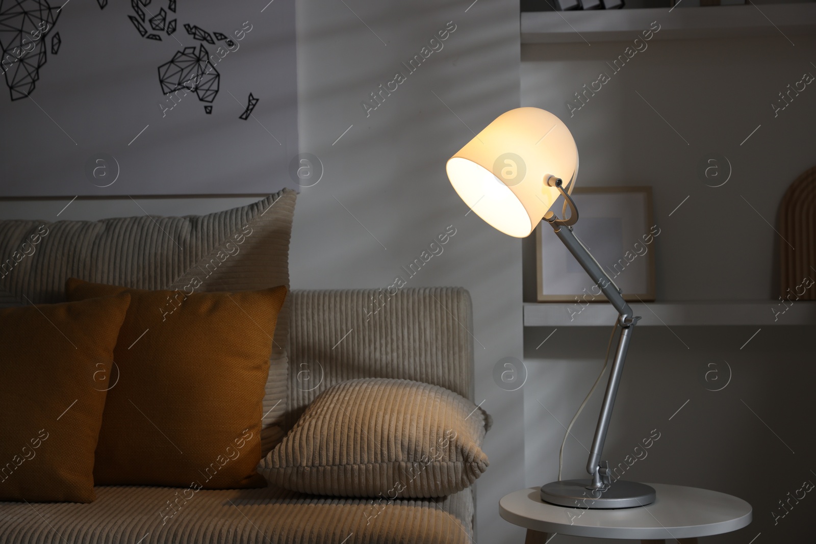 Photo of Stylish night lamp on side table near sofa in room. Interior design